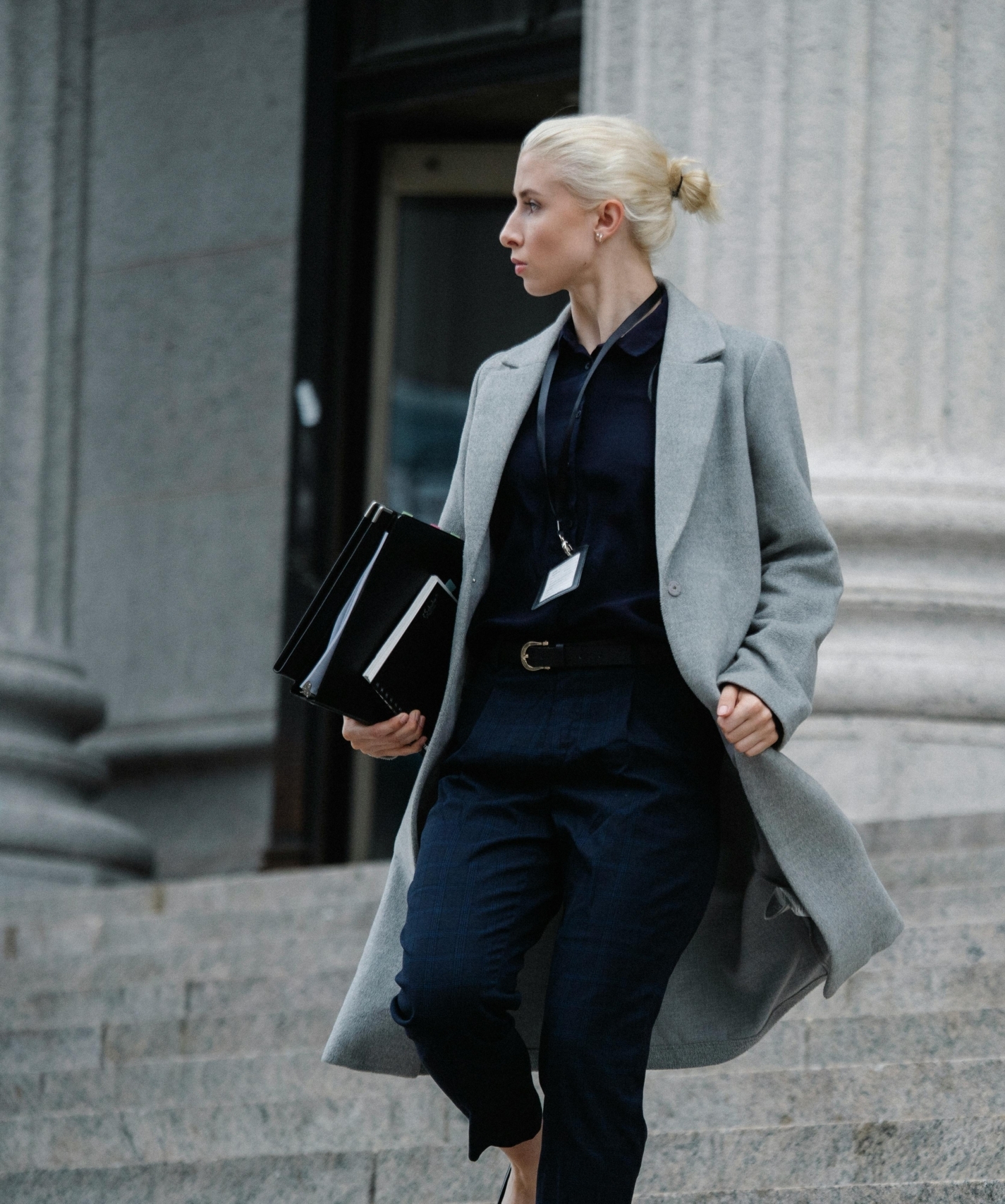 M.Sc. Rechtspsychologie: Begutachtung und Intervention. Eine Frau schaut in die Ferne. Sie steht auf einer Trepp vor einem Gerichtsgebäude.