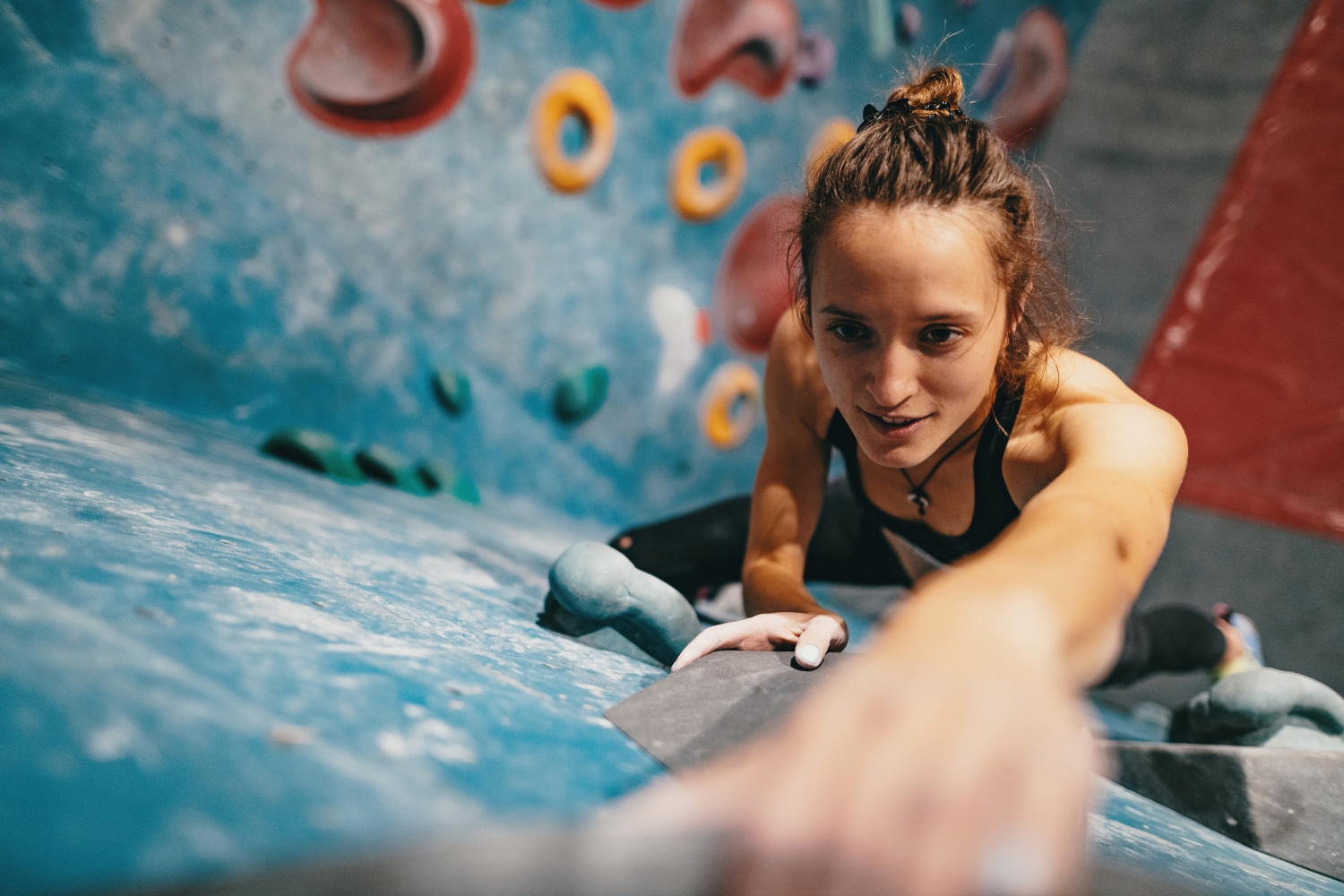 Eine junge Frau klettert an einer Wand in einer Boulderhalle